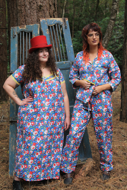 Two people wearing matching floral poppies nightdress with sleeves and pyjamas in forest scene platform.