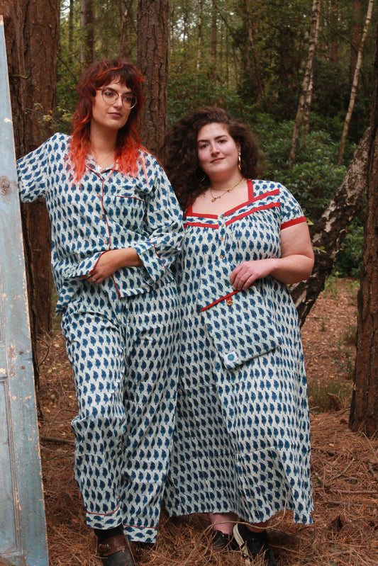 Two people wearing matching outfits in a forest setting. blue indigo nightie with sleeves maxi length and blue indigo pyjamas