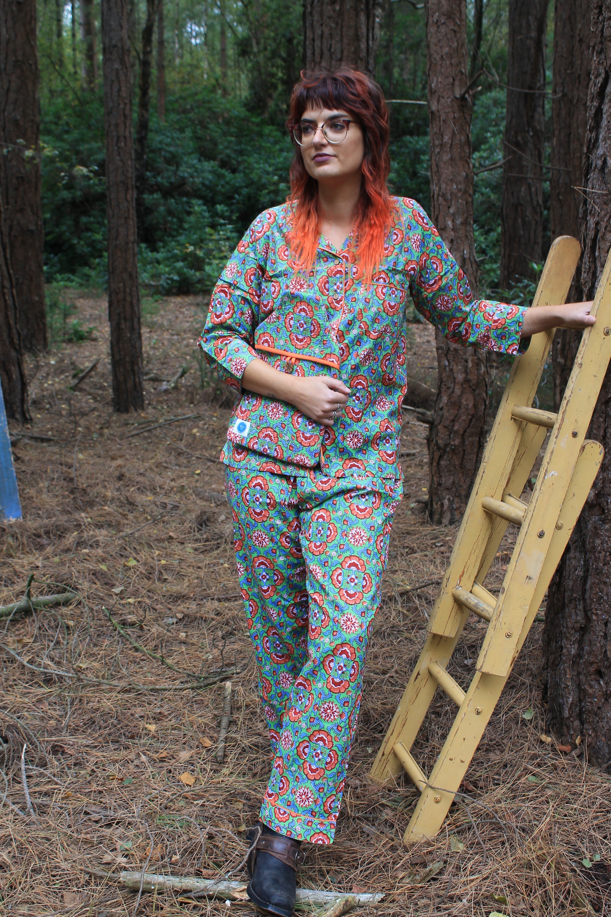 Size 12 model wearing hand block printed pyjamas, geometric pattern orange, green, full length trousers in forest